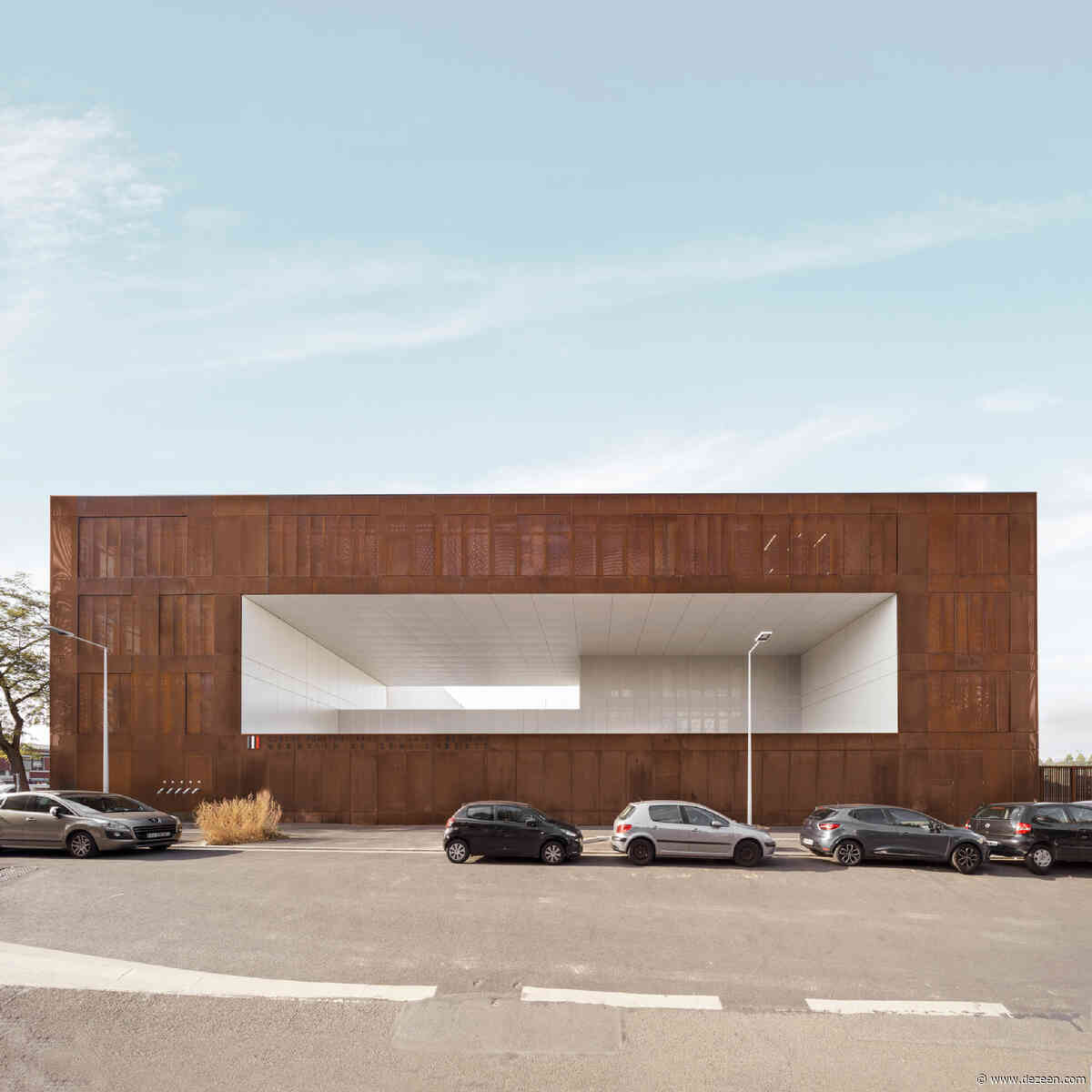 Prison clad in perforated weathering steel has pastel-coloured sports court