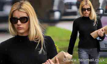 Emma Roberts looks stylish in a black sweater and statement boots