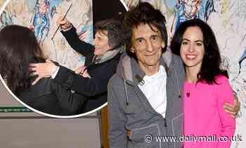 Ronnie Wood, 72, playfully attempts to scribble on his stunning wife Sally, 41, at art event