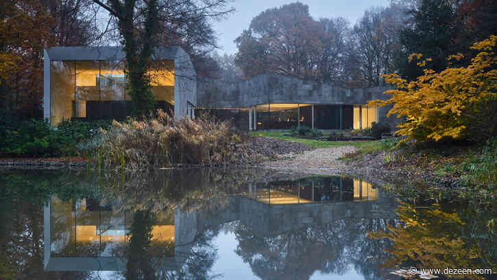 Forest house of stone and glass is reflected back in water