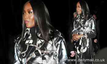 Naomi Campbell flashes her figure under a PVC trench coat as she attends Burberry's LFW show