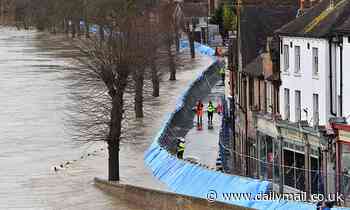 Locals watch as the Severn surges inches from the top of its flood barrier