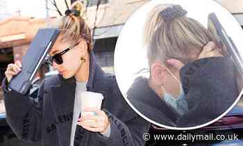 Hailey Bieber wears a MASK as she lands in New York then covers her face with an iPad
