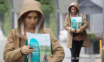 Lily Collins bundles up for the rainy weather in a light brown raincoat