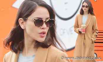 Eiza Gonzalez looks like a movie star in a tan coat and leather boots as she grabs an iced coffee