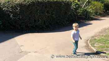 Boy waves at empty street as members of the public isolate due to coronavirus
