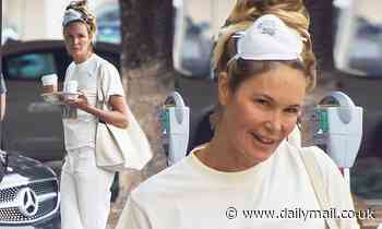 Elle Macpherson looks upbeat as she wears her face mask on her head after grabbing some coffees