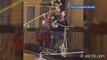 'Saluti!': Neighbors in Italy use long sticks to toast from their balconies amid COVID-19