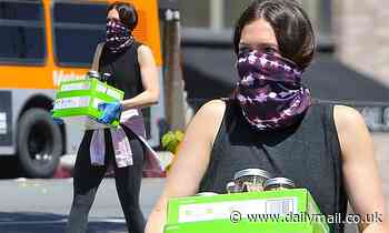 Mandy Moore shows off her muscular arms in a tank top as she carries two boxes of food