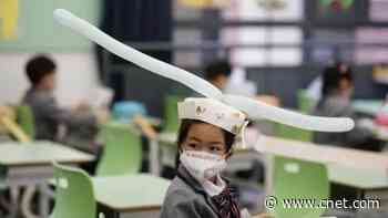 Kids in China head back to school wearing social-distancing hats     - CNET