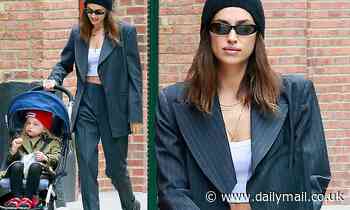 Irina Shayk teases her toned midriff in a white crop top beneath chic charcoal suit