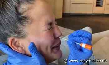 'It tickles!' Chrissy Teigen squeals and giggles as she gets her nose swabbed during COVID-19 test