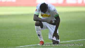 Marcus Thuram takes a knee after scoring in Bundesliga clash