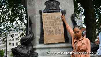 Sign taped over plaque that describes slave trader as ‘virtuous and wise’