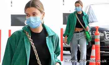 Hailey Bieber flaunts her toned tummy with a crop top and faded jeans