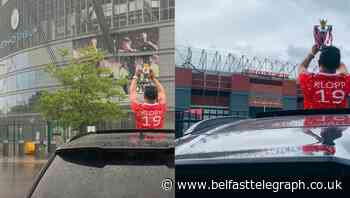 Liverpool fan takes replica Premier League trophy for photo at Old Trafford