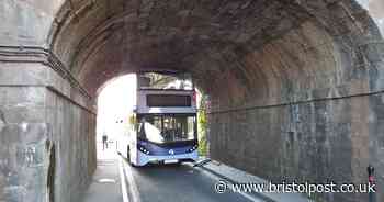 Live: Bus  with 'Stay Alert' on the front stuck under bridge