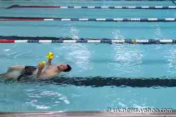 Man juggles balls while swimming backwards