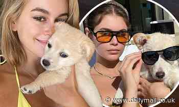 Kaia Gerber cuddles up to her rescue pup as she lounges by the pool in an olive green bikini