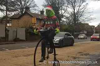 The Grinch arrives in Bolton on a penny farthing
