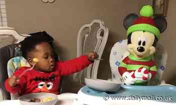 Sharing is caring! Adorable toddler offers his scrambled eggs to his Mickey Mouse doll