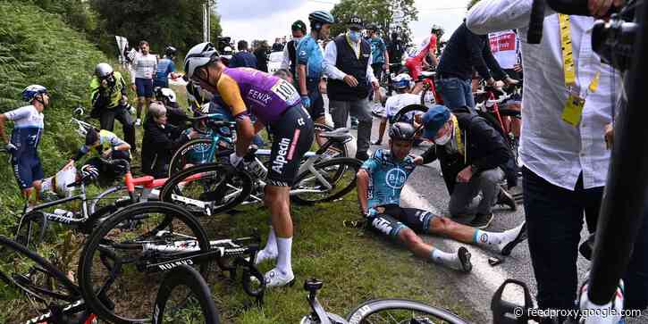 Oblivious Tour de France spectator holding a cardboard sign causes a gnarly crash that sends dozens of riders to the ground on the opening stage