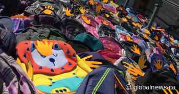 Backpacks line steps of legislative building to represent unmarked graves