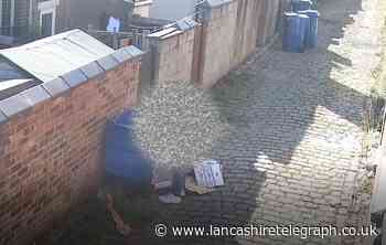 Blackburn: Man empties contents of blue bin in back alley