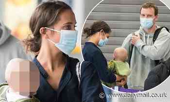 Alicia Vikander cradles a baby while at an airport with husband