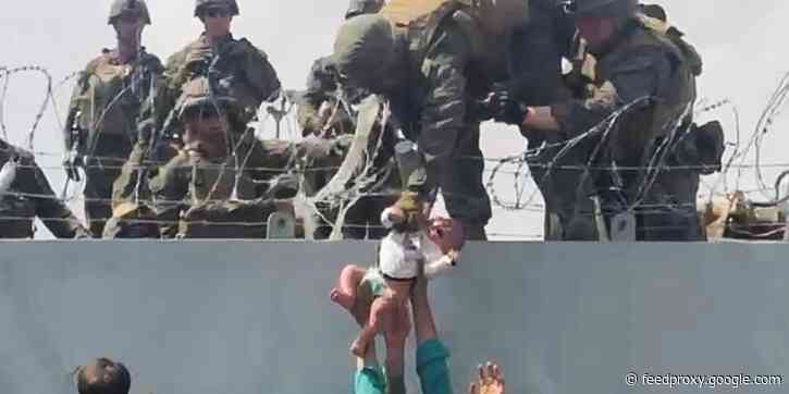 A baby that was photographed being passed to US soldiers over razor wire in Afghanistan has been safely reunited with their father
