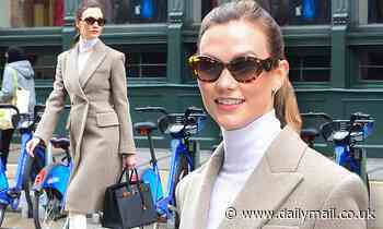 Karlie Kloss is photo-ready as she takes a walk through NYC in a long coat and knee-high white boots