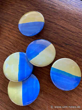 Kinder fertigen blau-gelbe Buttons für Flüchtlingshilfe