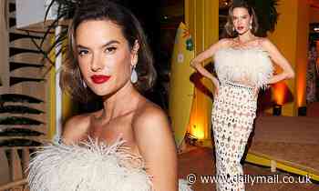Alessandra Ambrosio slips on a feather bandeau and quirky cut-out skirt during Cannes Film Festival
