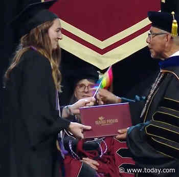Graduating students hand school president rainbow flags in protest of anti-LGBTQ staff policies