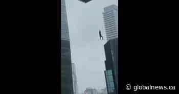 Videos show construction worker dangling from crane in Toronto
