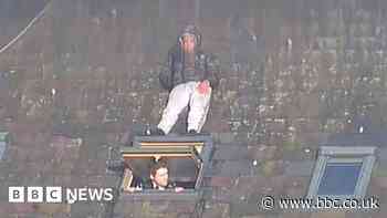 He's behind you - man hides from police on roof