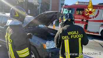 Fiamme dal cofano di un'auto parcheggiata in strada
