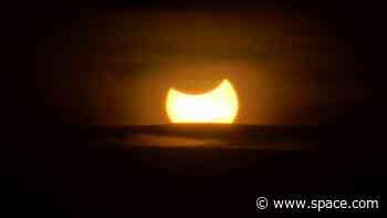 The moon blocks the sun in a rare hybrid solar eclipse today