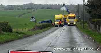 Double decker bus with passengers on it topples over into field