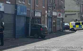 Blackburn road closed as car crashes into shop front
