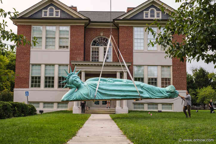 A crane lowered a reclining Statue of Liberty in Virginia Square this morning