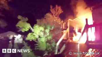 Moment police officer wakes up people in burning house