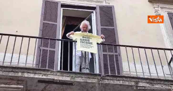 Grillo a Roma mostra una maglia gialla sul reddito universale dal balcone della sede M5s