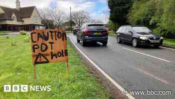 Sign warns of potholes outside Rolls-Royce showroom