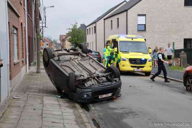 Auto over de kop na botsing tegen geparkeerde wagen: vrouw gewond naar ziekenhuis
