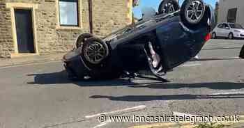 Car on its roof after crash at busy junction