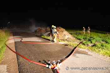 Berg met riet vliegt in brand langs de weg