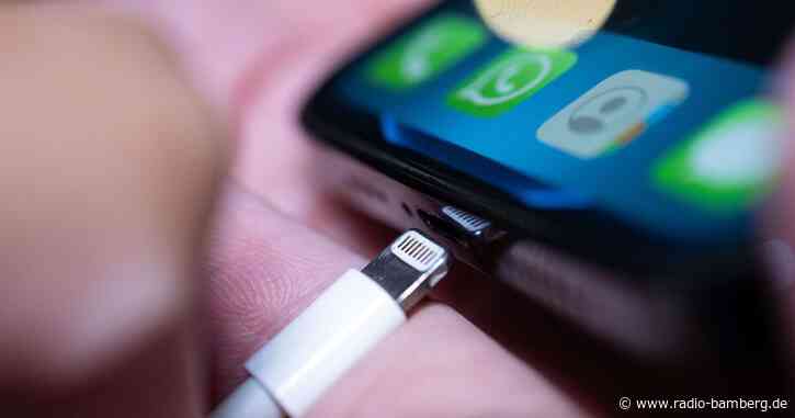 Junger Mann lädt sein Handy an offenem Stromkasten