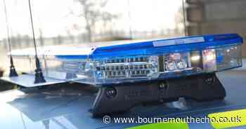 Marked police car and car crashes on busy Poole road