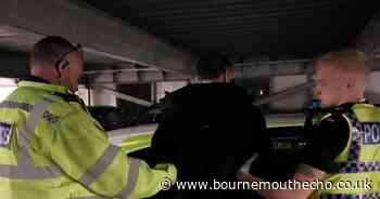 Wanted man detained after being caught breaking into car